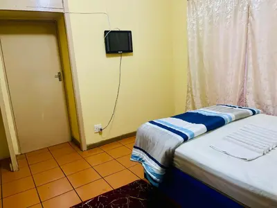 a small room with a bed and a tv on the wall at Galaxy Guesthouse Pretoria North in Pretoria