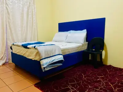 a bed with a blue headboard in a room at Galaxy Guesthouse Pretoria North in Pretoria