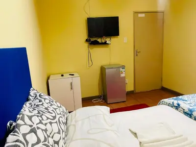 a bedroom with a bed and a television on the wall at Galaxy Guesthouse Pretoria North in Pretoria
