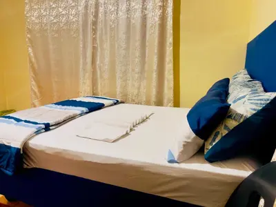 a bed with blue and white pillows next to a window at Galaxy Guesthouse Pretoria North in Pretoria