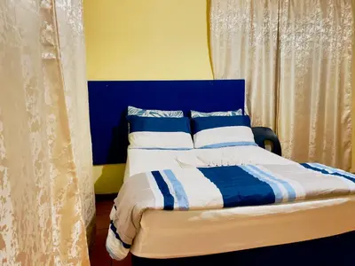 a bedroom with a blue and white bed and curtains at Galaxy Guesthouse Pretoria North in Pretoria