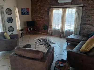 a living room with couches and a zebra on the floor at Maridadi House in Marloth Park