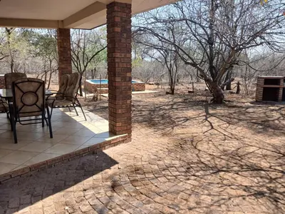 a patio with chairs and a table and a tree at Maridadi House in Marloth Park