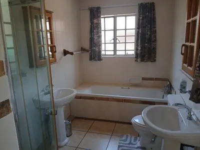 a bathroom with a tub and a toilet and a sink at Maridadi House in Marloth Park