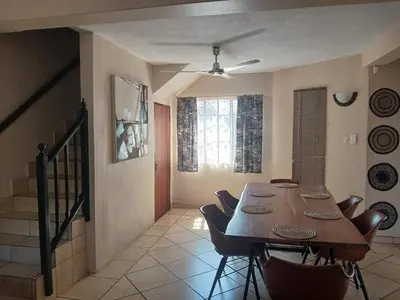 a dining room with a wooden table and chairs at Maridadi House in Marloth Park
