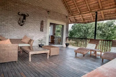 a patio with a couch and chairs on a deck at Mad Safari Bush Camp in Phalaborwa