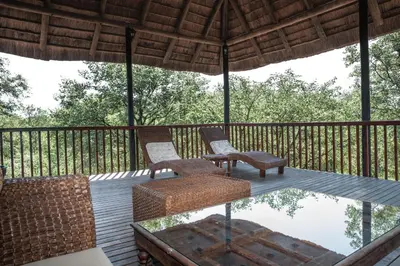 two chairs and a table on a deck with a glass table at Mad Safari Bush Camp in Phalaborwa
