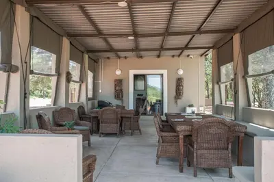 a dining room with tables and chairs and windows at Mad Safari Bush Camp in Phalaborwa