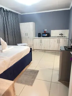 a bedroom with a large bed and a kitchen at The Light Guest House in Midrand