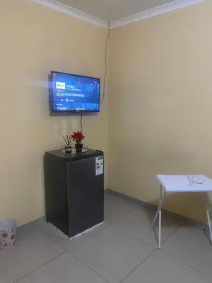 a room with a tv on the wall and a table at The Light Guest House in Midrand