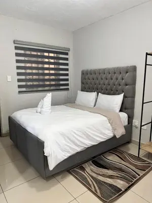 a bedroom with a large bed with white sheets and pillows at The Light Guest House in Midrand
