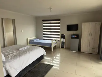 a bedroom with a bed and a chair and a television at The Light Guest House in Midrand