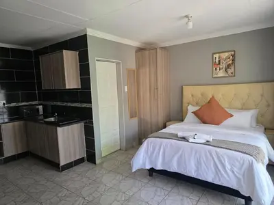 a bedroom with a large bed and a kitchen at House 224 Lodge in Driekop