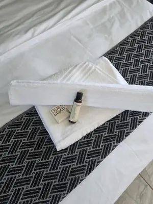 a white bed with a bottle of perfume on it at House 224 Lodge in Driekop