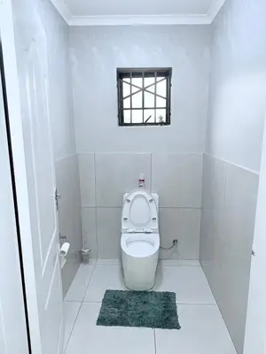 a white bathroom with a toilet with a window at Country Farm House in Delmas