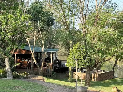 a log cabin with a porch and trees at Leopard Chalets Hippo Waterfront Lodge in Nelspruit