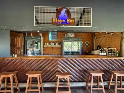 a bar with wooden stools in a restaurant at Leopard Chalets Hippo Waterfront Lodge in Nelspruit