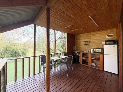 a kitchen with a table and a refrigerator on a deck at Leopard Chalets Hippo Waterfront Lodge in Nelspruit