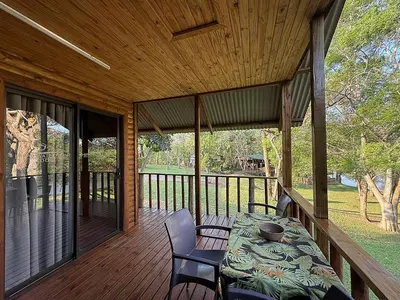 a wooden deck with a table and chairs on it at Leopard Chalets Hippo Waterfront Lodge in Nelspruit