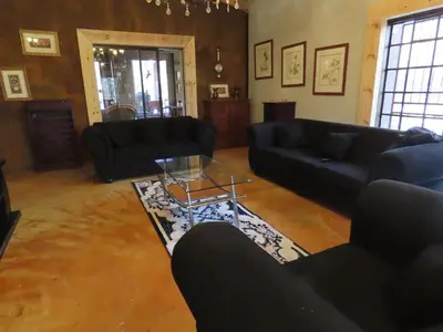a living room with black couches and a table at Unique Kruger Hide & Spa in Marloth Park