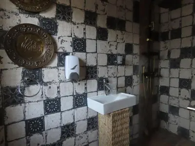 a bathroom with a sink and a tile wall at Unique Kruger Hide & Spa in Marloth Park