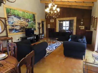 a living room with black furniture and a chandelier at Unique Kruger Hide & Spa in Marloth Park