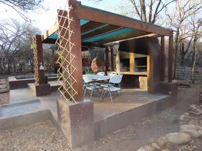 a shelter with a table and chairs in a park at Unique Kruger Hide & Spa in Marloth Park