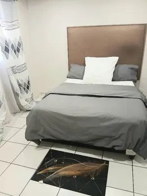 a bed sitting on a tiled floor in a bedroom at Tonta house in Pretoria