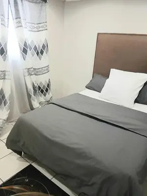 a bedroom with a bed with a gray comforter at Tonta house in Pretoria