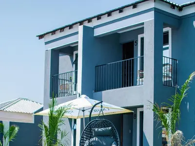 a blue house with a balcony and an umbrella at Overflow Accommodation Lodge in Louis Trichardt