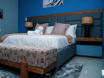 a bedroom with a large bed with blue walls at Overflow Accommodation Lodge in Louis Trichardt