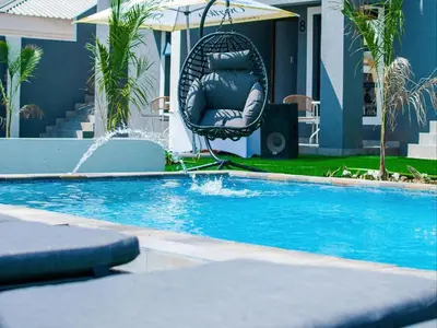 a chair sitting in a swing by a swimming pool at Overflow Accommodation Lodge in Louis Trichardt