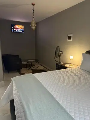 a bedroom with a white bed and a tv on the wall at Ella Guest House in Pretoria