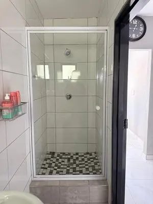a shower with a glass door in a bathroom at Ella Guest House in Pretoria