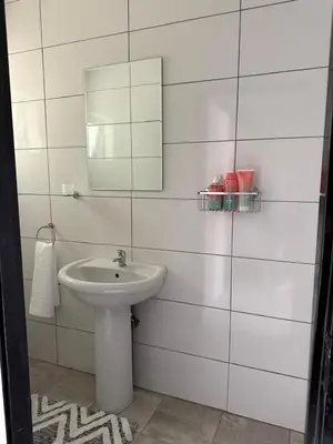 a white bathroom with a sink and a mirror at Ella Guest House in Pretoria