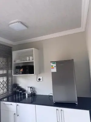 a kitchen with a black counter top and a refrigerator at Ella Guest House in Pretoria
