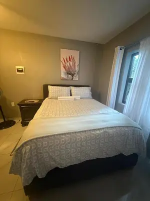 a large bed in a bedroom with a window at Ella Guest House in Pretoria