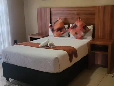 a bedroom with a large bed with a wooden headboard at Villa Hadassa and Spa in Burgersfort