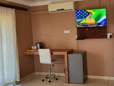 a room with a desk and a tv on the wall at Villa Hadassa and Spa in Burgersfort