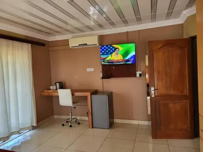 a room with a desk and a tv on the wall at Villa Hadassa and Spa in Burgersfort