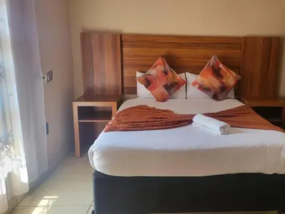 a bedroom with a large bed with a wooden headboard at Villa Hadassa and Spa in Burgersfort