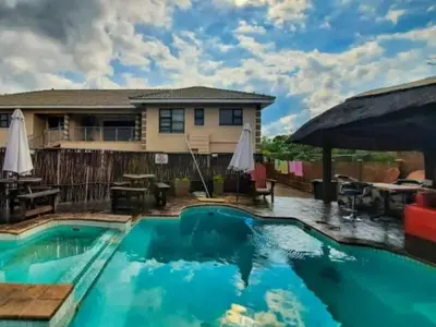 a swimming pool with a house in the background at Villa Hadassa and Spa in Burgersfort