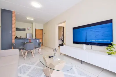 a living room with a large flat screen tv on a wall at Prime Ridge in Midrand