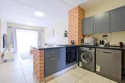 a kitchen with a washer and dryer next to a brick wall at Prime Ridge in Midrand