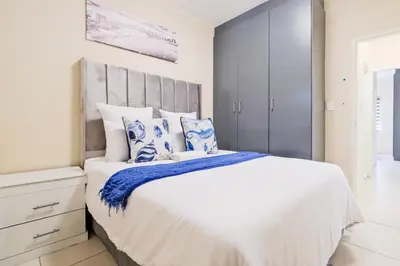 a bedroom with a large bed with blue and white pillows at Prime Ridge in Midrand