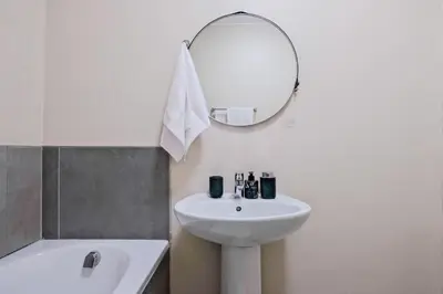 a white bathroom with a sink and a mirror at Prime Ridge in Midrand