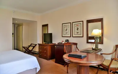 a hotel room with a bed and a desk with a table at Hotels Near OR Tambo Airport Booked Easy in Johannesburg