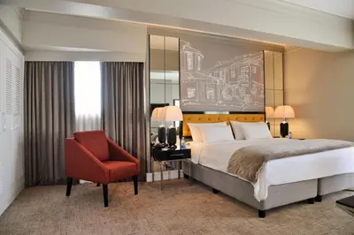 a bedroom with a bed and a red chair at Hotels Near OR Tambo Airport Booked Easy in Johannesburg
