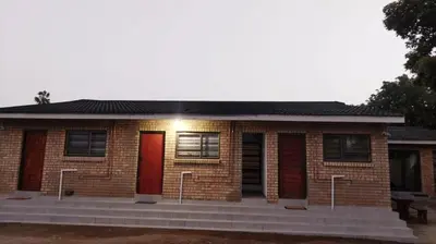 a brick house with a red door and stairs at C-Rane Lodge - E in Phalaborwa