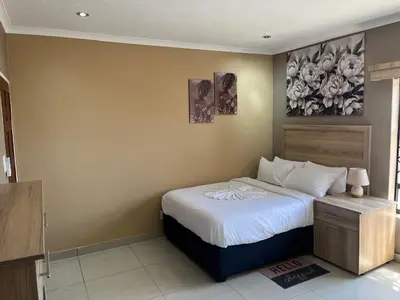 a bedroom with a bed and a painting on the wall at Zonke Bonke Guest House in Burgersfort